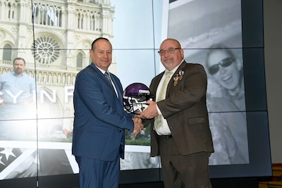 Two men pose with a helmet