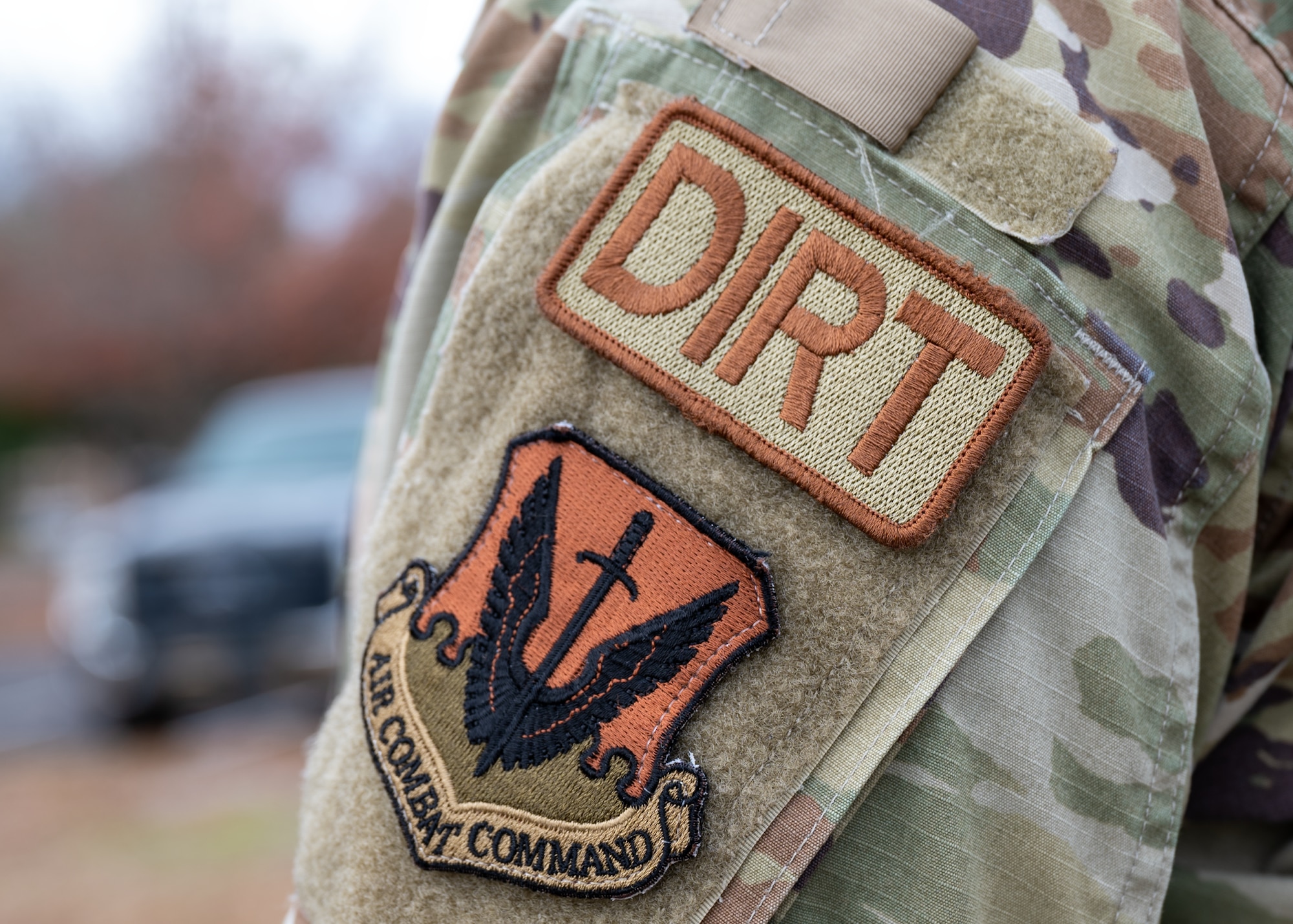 A close up of a patch that says DIRT on the side of a man's arm.