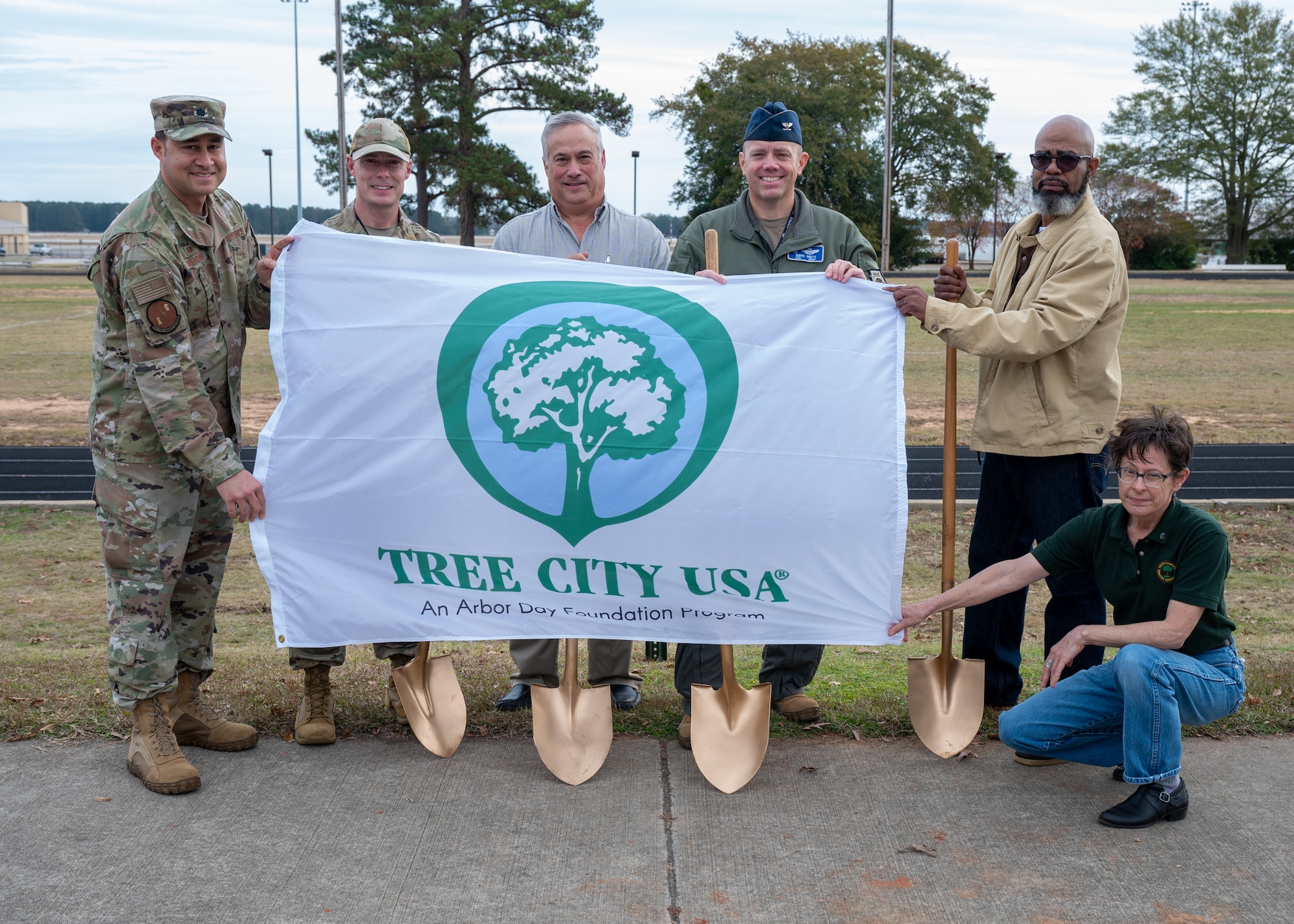 A group of people hold a flag that says Tree City USA.