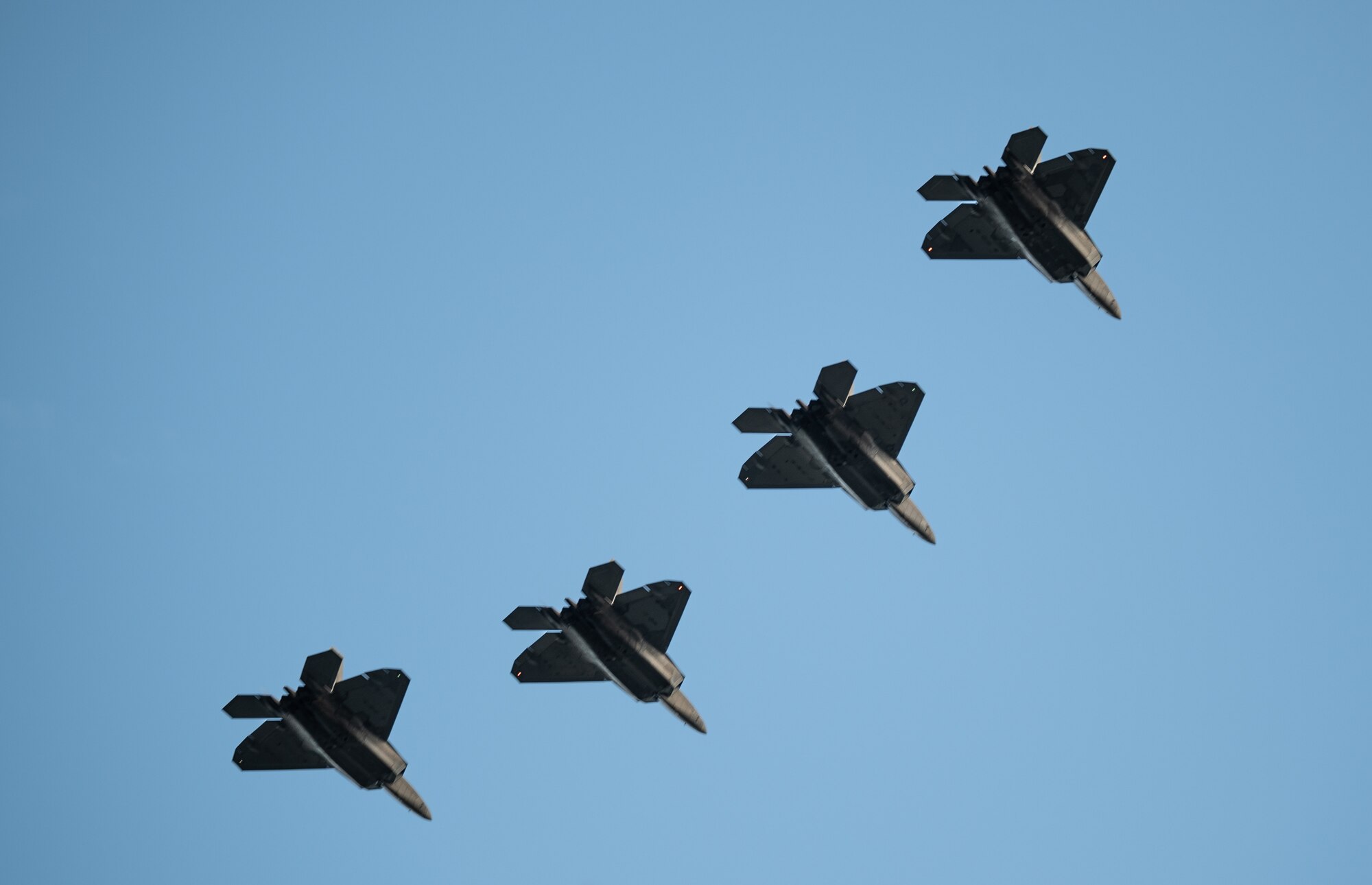 F-22 Raptors assigned to the Hawaii Air National Guard perform a flyover during a December 7th Remembrance Ceremony at Joint Base Pearl Harbor-Hickam, Hawaii, Dec. 7, 2023. This was the 82nd anniversary of the attacks on Pearl Harbor and Hickam Field that claimed the lives of 189 service members. (U.S. Air Force photo by Staff Sgt. Alan Ricker)
