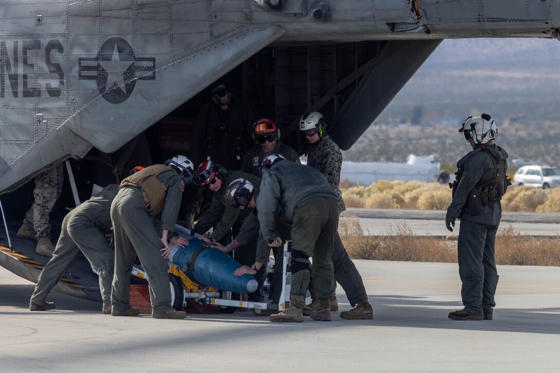 U.S. Marines with the 3rd Marine Aircraft Wing All Type Model Series Armament Team unload ordnance from a CH-53E Super Stallion helicopter at a forward arming and refueling point in support of Exercise Steel Knight 23.2 at Inyokern Airfield, California, Dec. 2, 2023. ATAT is comprised of aviation ordnance Marines qualified to load and arm every type model series platform in the 3rd MAW fleet. Steel Knight 23.2 is a three-phase exercise designed to train I Marine Expeditionary Force in the planning, deployment and command and control of a joint force against a peer or near-peer adversary combat force and enhance existing live-fire and maneuver capabilities of the Marine Air-Ground Task Force. (U.S. Marine Corps photo by Lance Cpl. Jennifer Sanchez)
