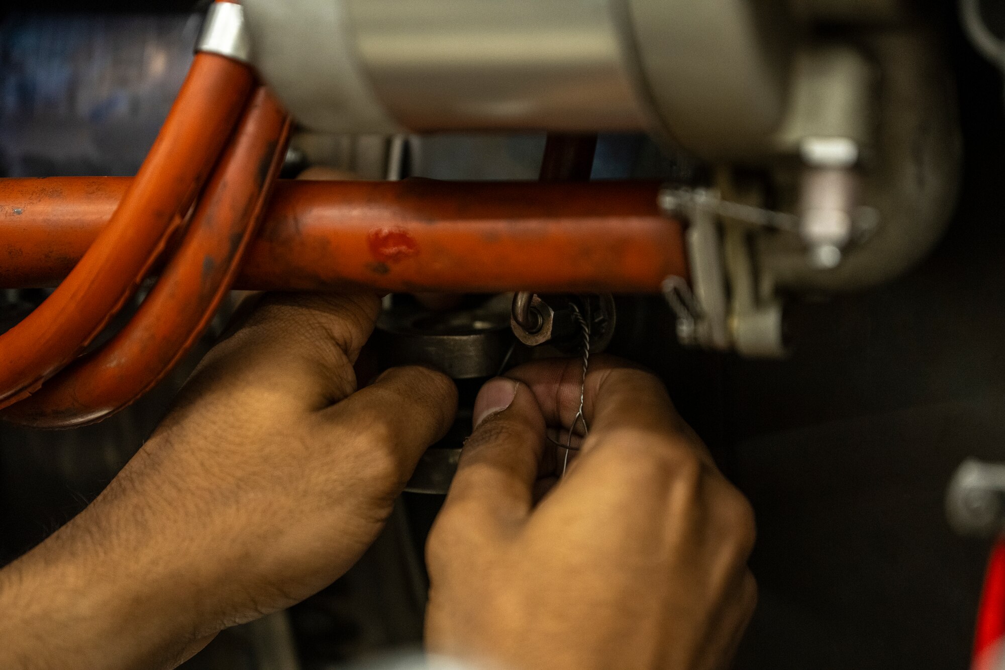 A photo of a persons hands placing something inside of an aircraft engine.