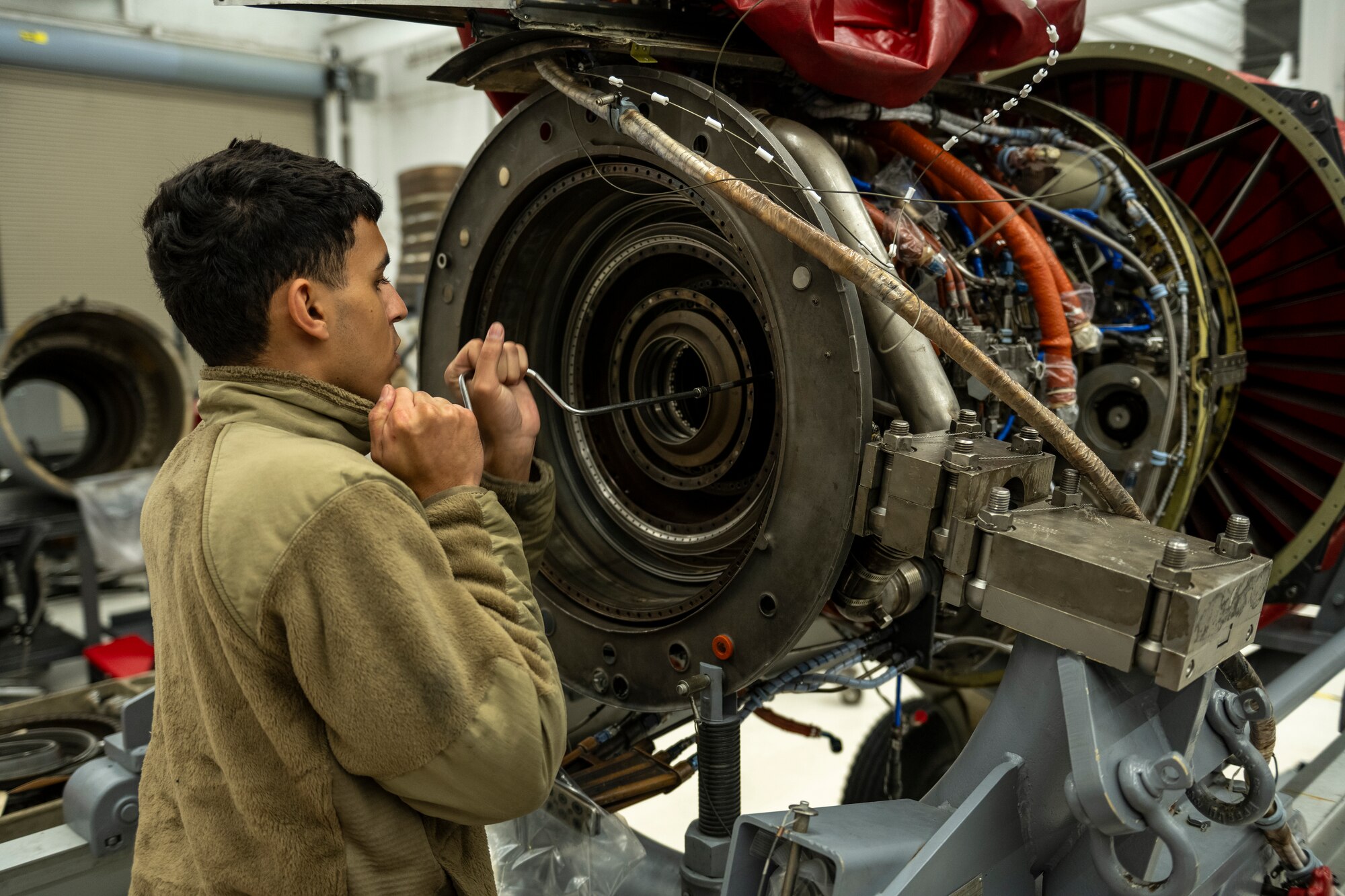 A photo of an Airman cranking a tool in an aircraft engine.