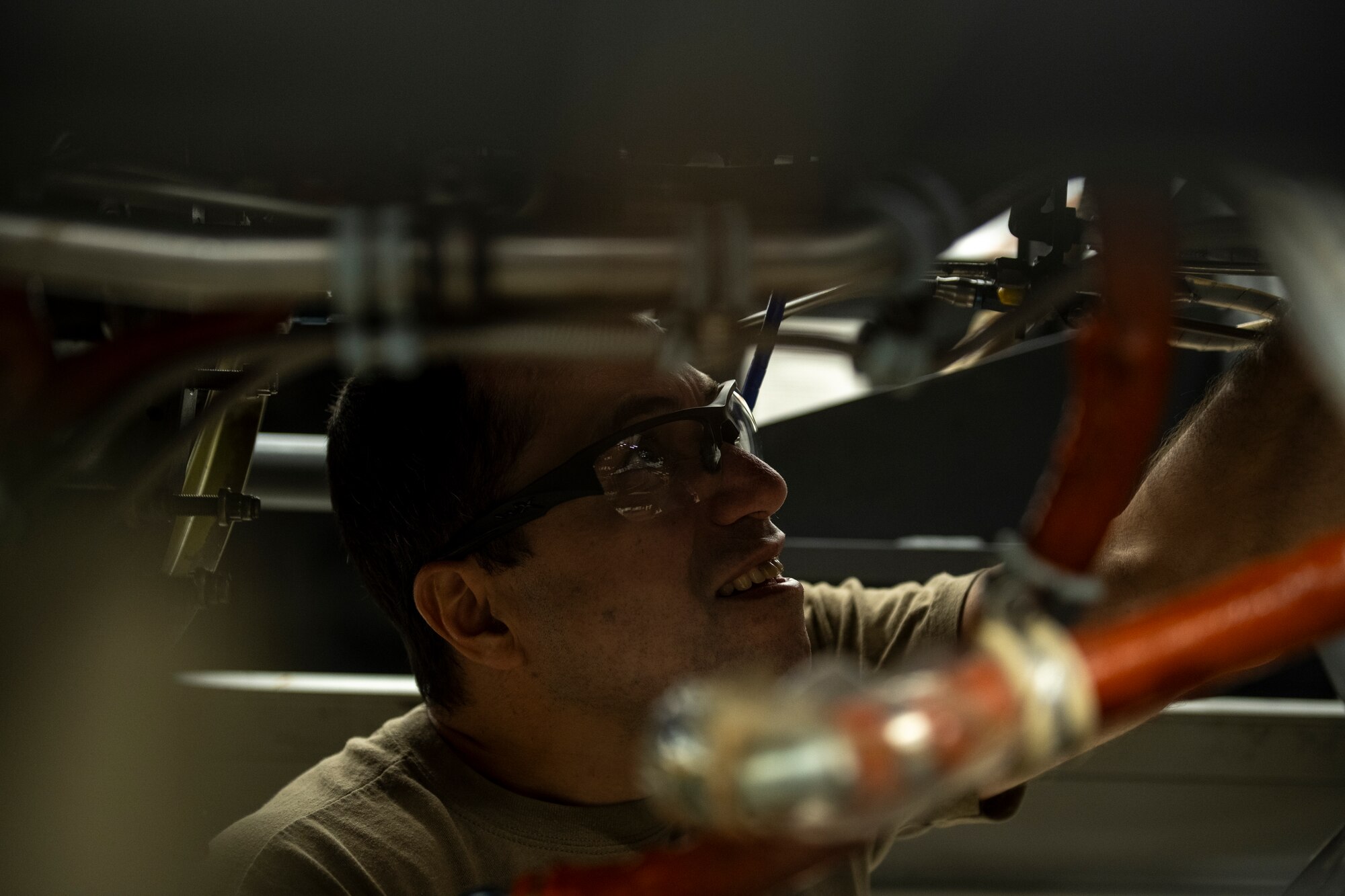 A photo of a person looking up at something inside an engine.