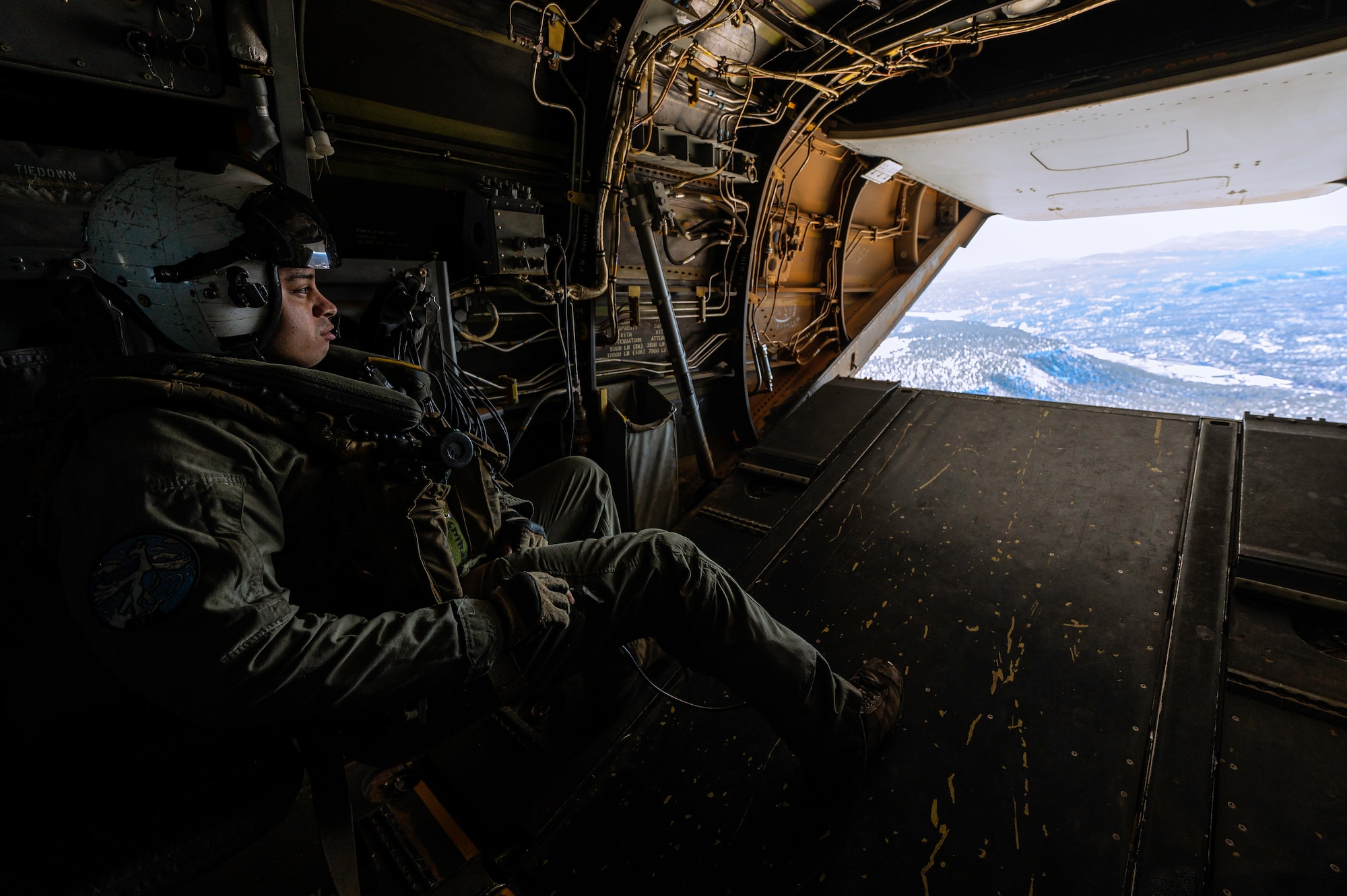 Man looks out of helicopter ramp in flight.
