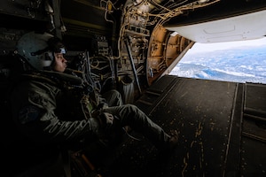 Man looks out of helicopter ramp in flight.