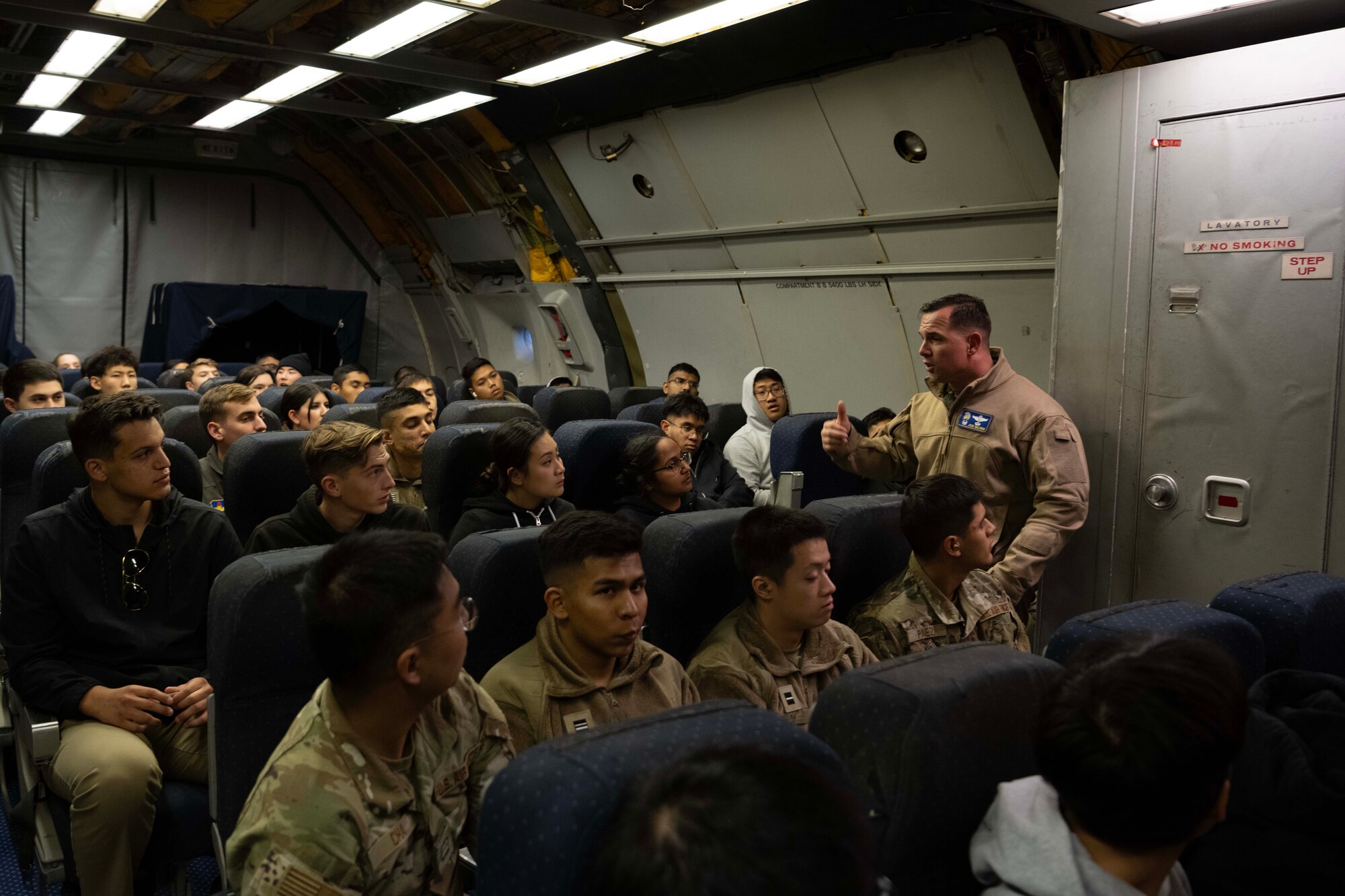 An Airman talks to cadets on a military aircraft