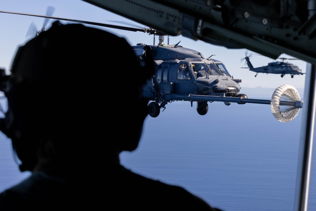 U.S. Air Force Master Sgt. Daniel Ibarra, an aircraft loadmaster specialist with 39th Rescue Squadron, 920th Rescue Wing, observes a HH-60G Pave Hawk aircraft with 301st Rescue Squadron, 920th Rescue Wing, receive fuel from a HC-130J Combat King II aircraft with 39th Rescue Squadron, 920th RW, during joint combat search and rescue training in support of Exercise Steel Knight 23.2 off the coast of San Diego, California, Dec. 5, 2023. Steel Knight 23.2 is a three-phase exercise designed to train I Marine Expeditionary Force in the planning, deployment and command and control of a joint force against a peer or near-peer adversary combat force and enhance existing live-fire and maneuver capabilities of the Marine Air-Ground Task Force. (U.S. Marine Corps photo by Lance Cpl. Jennifer Sanchez)