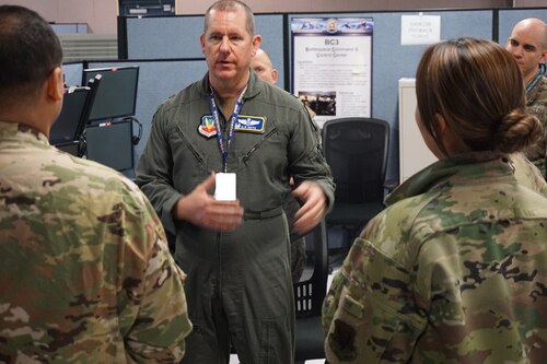 Alt text: military members standing around computers talking