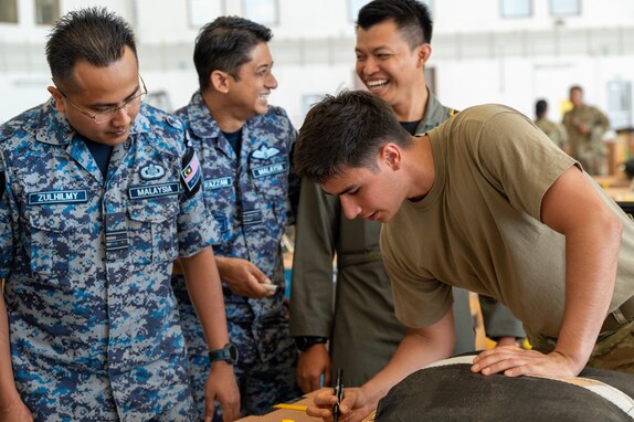 Photo of Royal Malaysian Air Force and U.S. Air Force personnel rigging an Operation Christmas Drop bundle for air drop