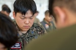 Photo of a Republic of Korea Air Force noncommissioned officer helping bundle an Operation Christmas Drop.