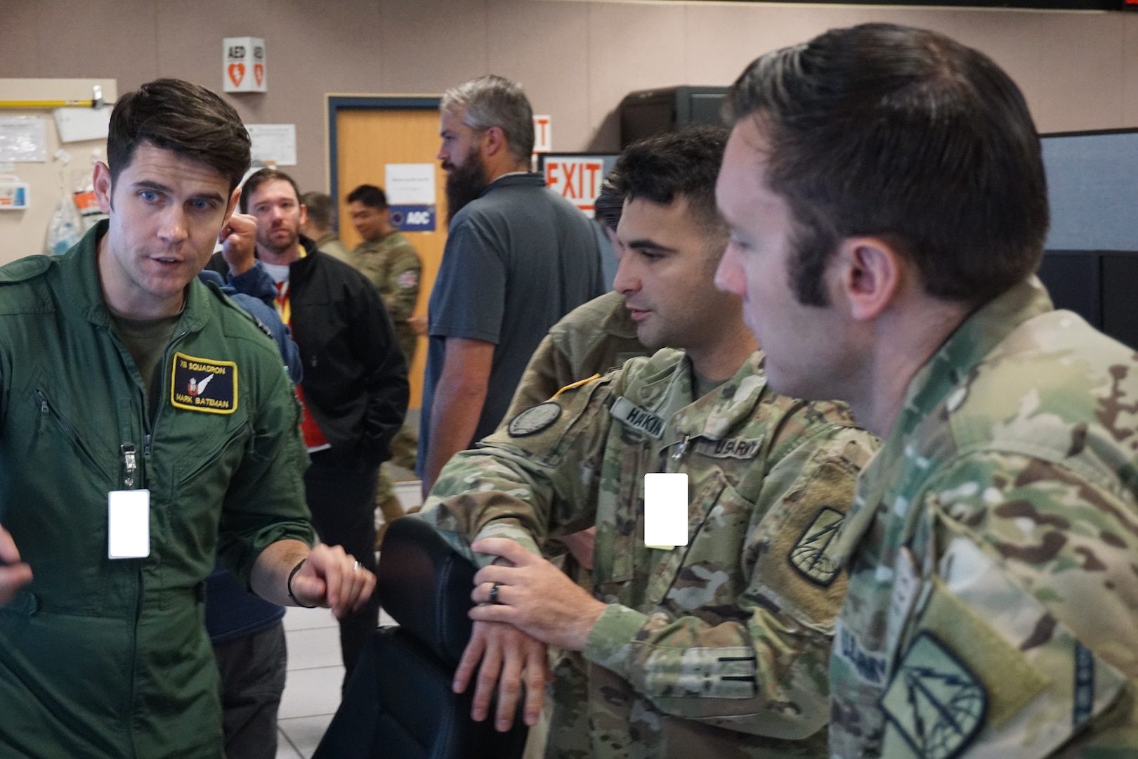 uniformed military members talking near flight simulators