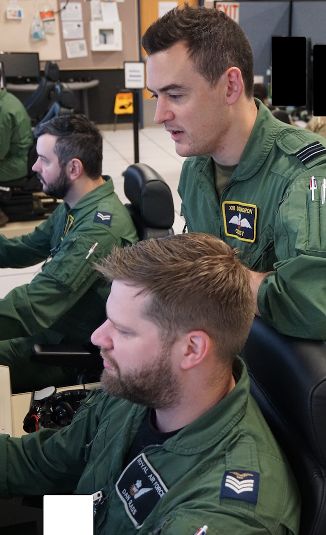 uniformed military members flying flight simulators
