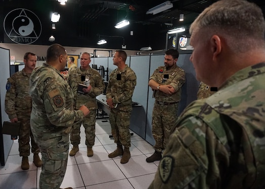  uniformed military members talk while standing in semicircle