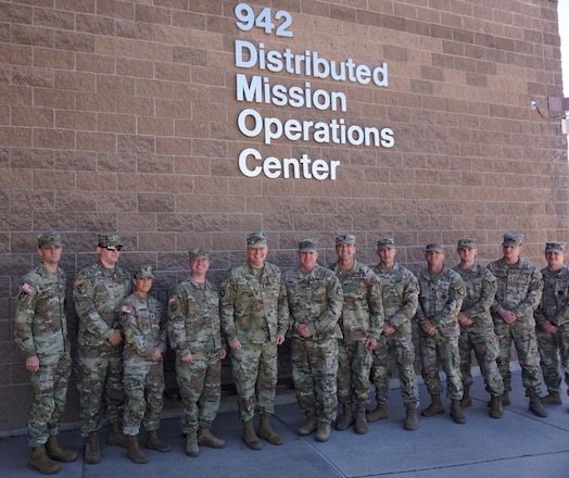  Alt text: uniformed military members stand in front of brick building with lettering “942 Distributed Mission Operations Center”