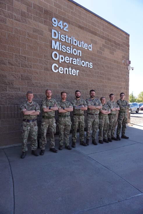  Alt text: uniformed military members stand in front of brick building with lettering “942 Distributed Mission Operations Center”