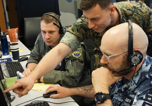  photo: three uniformed military members work at computers