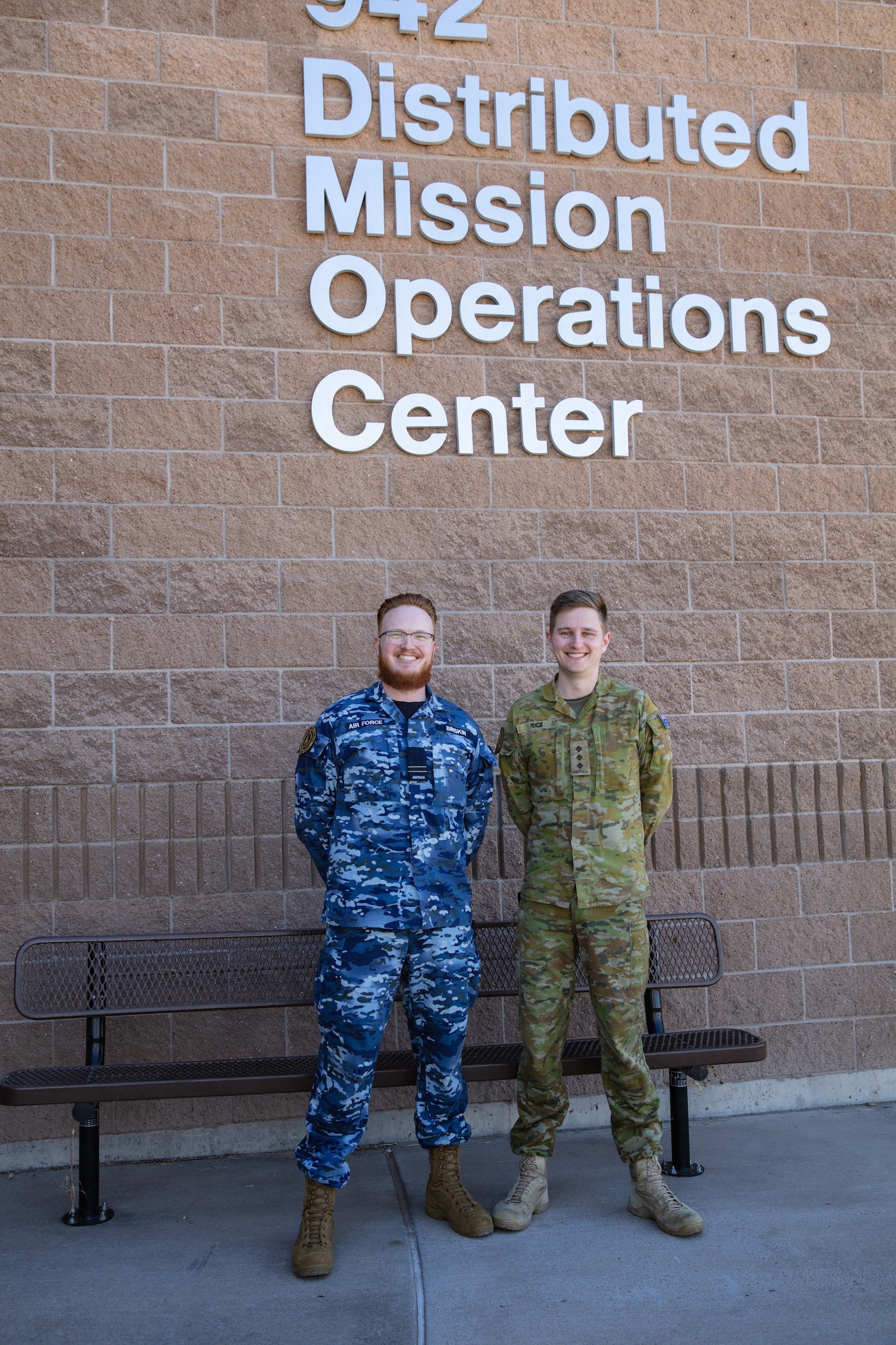 uniformed military members stand in front of brick building with lettering “942 Distributed Mission Operations Center”