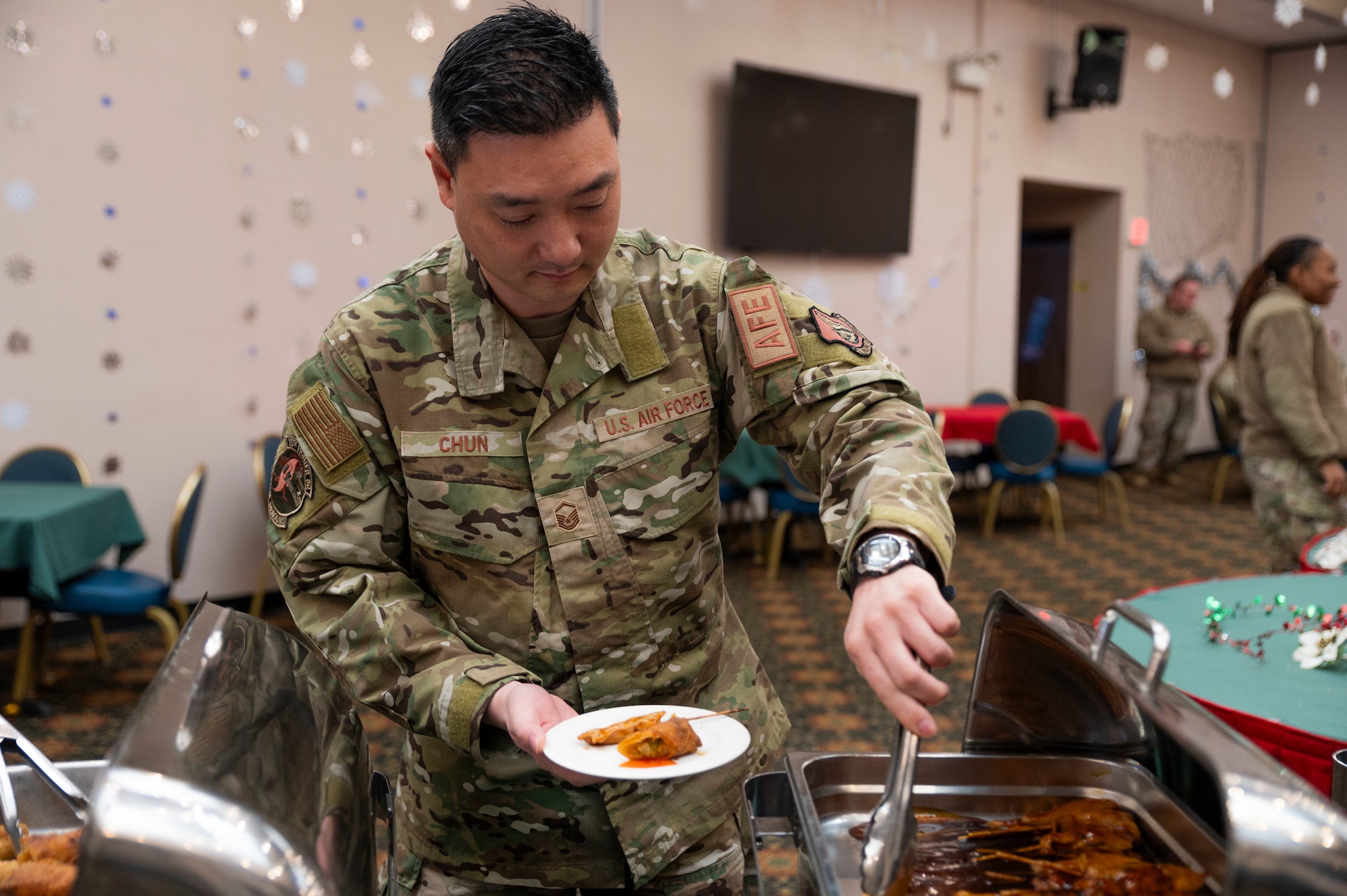 U.S. Air Force Master Sgt. David Chung, 51st Operational Support Squadron air crew flight equipment flight chief, grabs food during the 51st Fighter Wing Holiday Reception at Osan Air Base, Republic of Korea, Dec. 6, 2023.