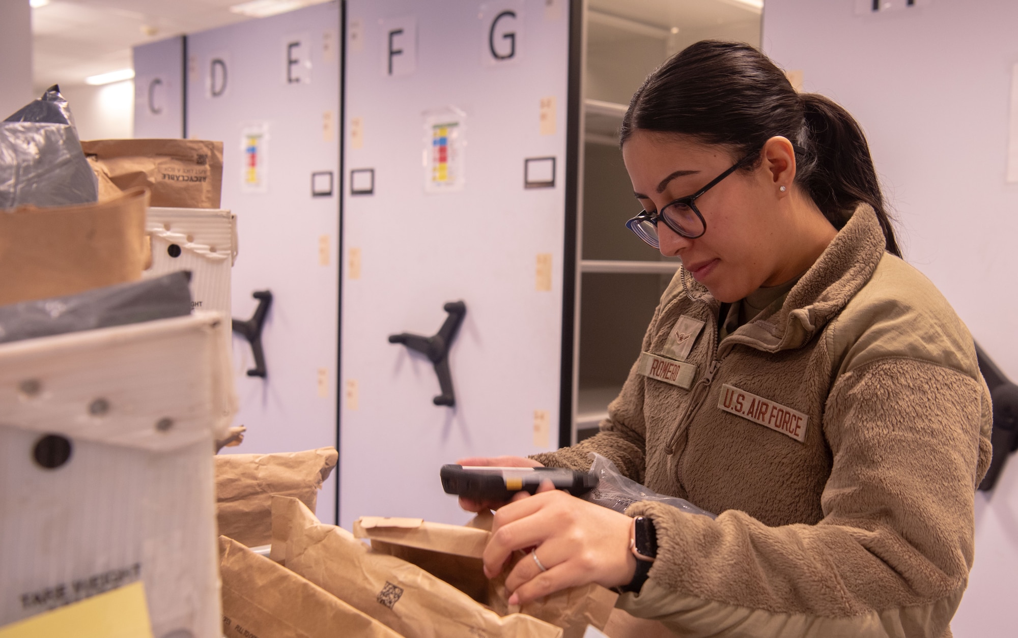 A military postal clerk, sorts through inbound packages at Ramstein Air Base
