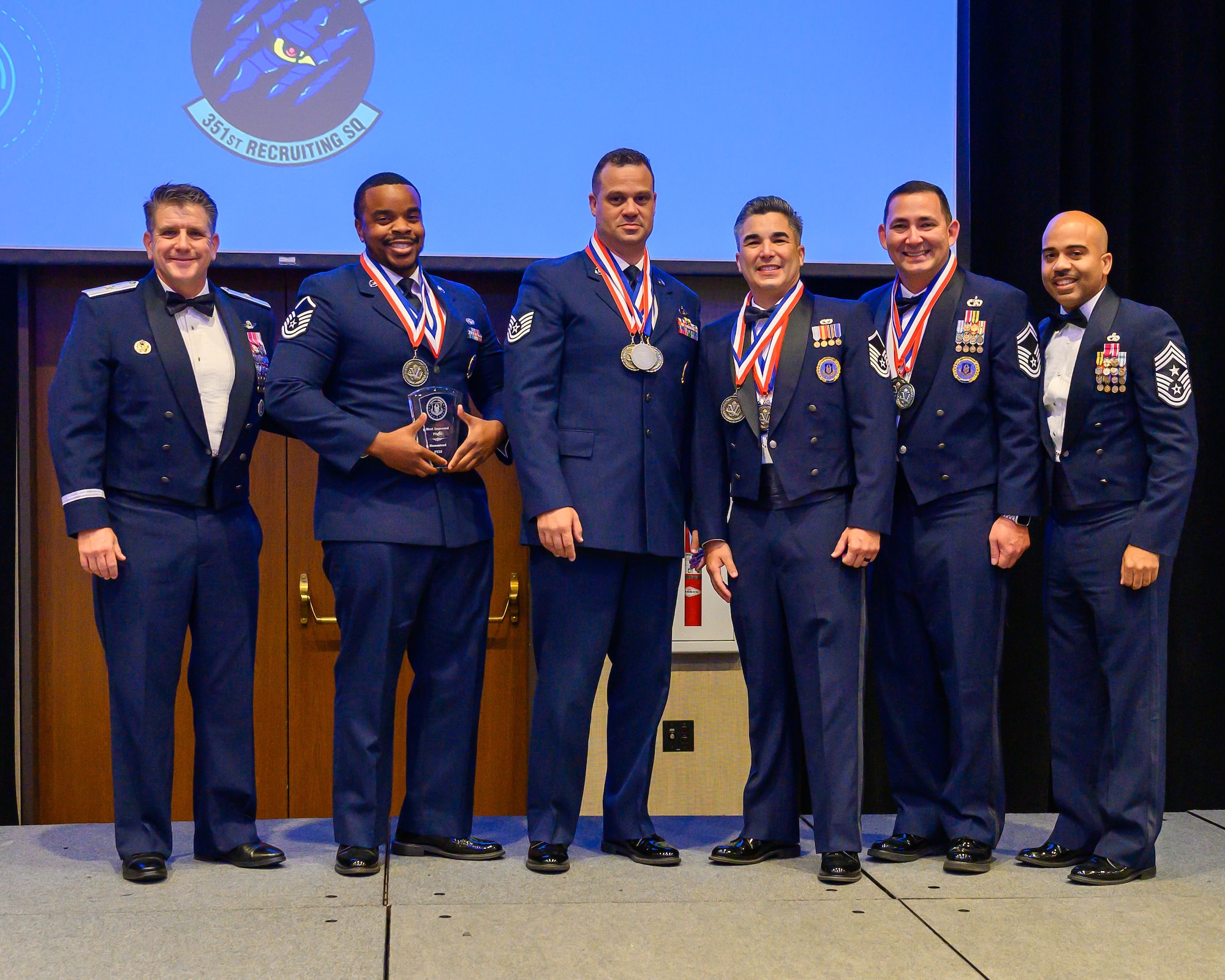 Brig Gen Christopher Amrhein and AFRC Command Chief Israel Nuñez present the Most Improved Flight award to MSgt Erick Williams, TSgt Bryant Guardia, MSgt Jaime Gomez Lopez, and SMSgt Chase Kaiuwailani during the 367 Recruiting Group Awards ceremony. This prestigious award recognizes the team's exemplary achievement of an 83% increase in recruitments in Fiscal Year 23, underscoring their significant contribution to the Air Force Reserve Command's recruitment efforts. (U.S. Air Force photo by Master Sgt. Bobby Pilch)