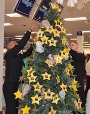 Sailors place ornaments on the Holiday Memorial Tree at Naval Station Great Lakes.