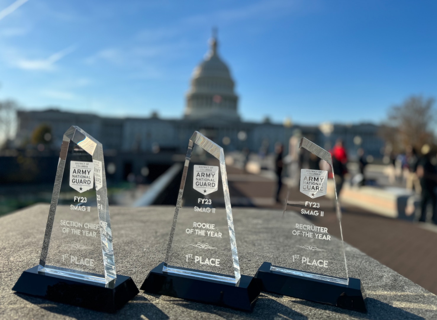 Three glass awards sit with the U.S. Capitol in the background