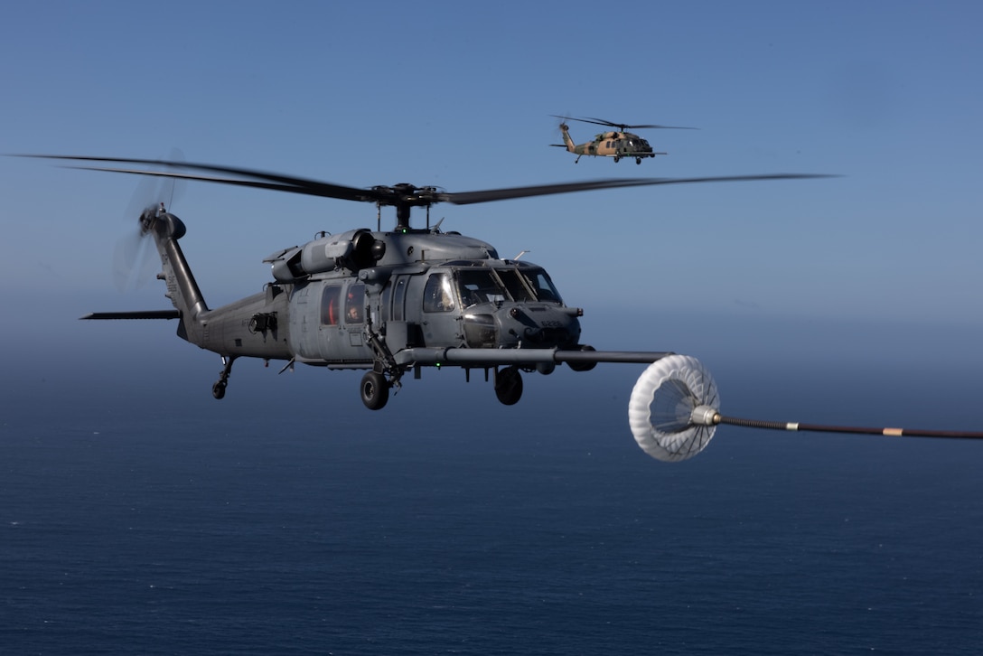 U.S. Air Force HH-60G Pave Hawk helicopters assigned to 301st Rescue Squadron, 920th Rescue Group, 920th Rescue Wing, conduct a helicopter air-to-air refueling from an HC-130J Combat King II assigned to 39th RQS, 920th RQW, during Exercise Steel Knight 23.2, in conjunction with Exercise Distant Fury Stallion 23.2, off the coast of San Diego, Dec. 7, 2023. Steel Knight 23.2 is a three-phase exercise designed to train I Marine Expeditionary Force in the planning, deployment and command and control of a joint force against a peer or near-peer adversary combat force and enhance existing live-fire and maneuver capabilities of the Marine Air Ground Task Force.  (U.S. Marine Corps photo by Lance Cpl. Samantha Devine)