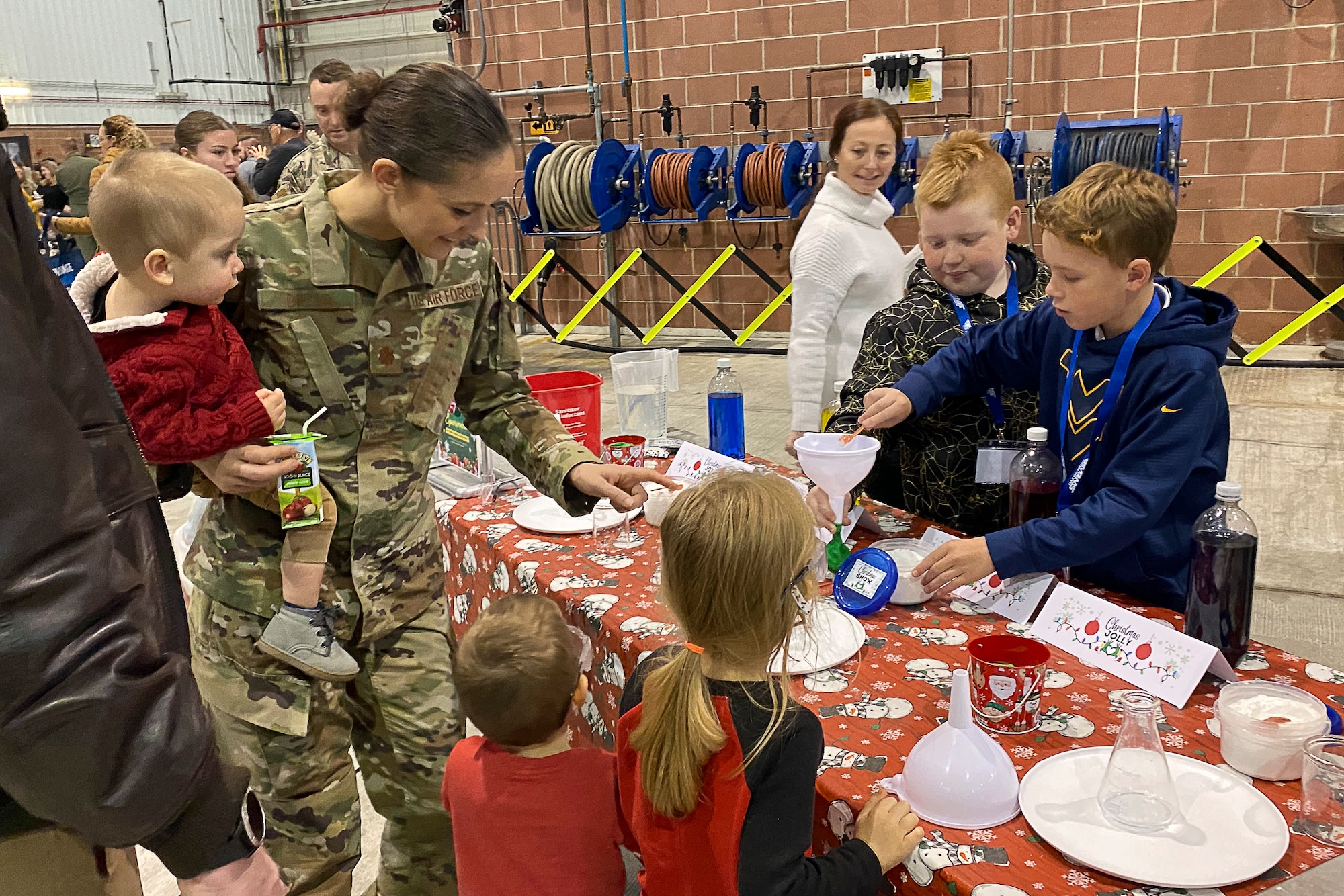 a women holds her young son as other children look at STEM activiites on a table