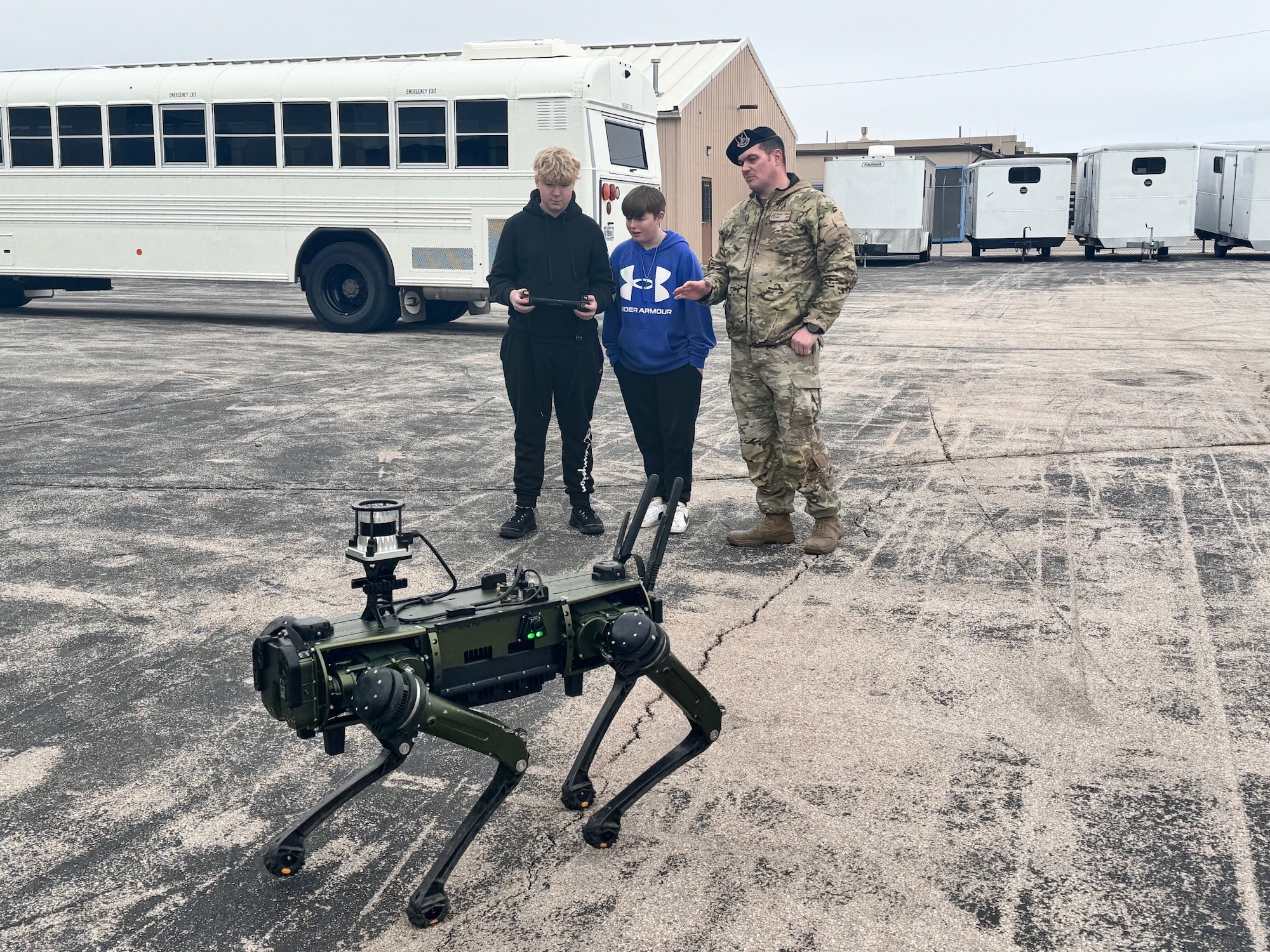 Students from Douglas Middle School operate a Quadrupedal Unmanned Ground Vehicle with assistance from Master Sgt. Nathan Londak, a 28th Security Forces Squadron installation security section chief, at Ellsworth Air Force Base, South Dakota, Dec. 5, 2023.