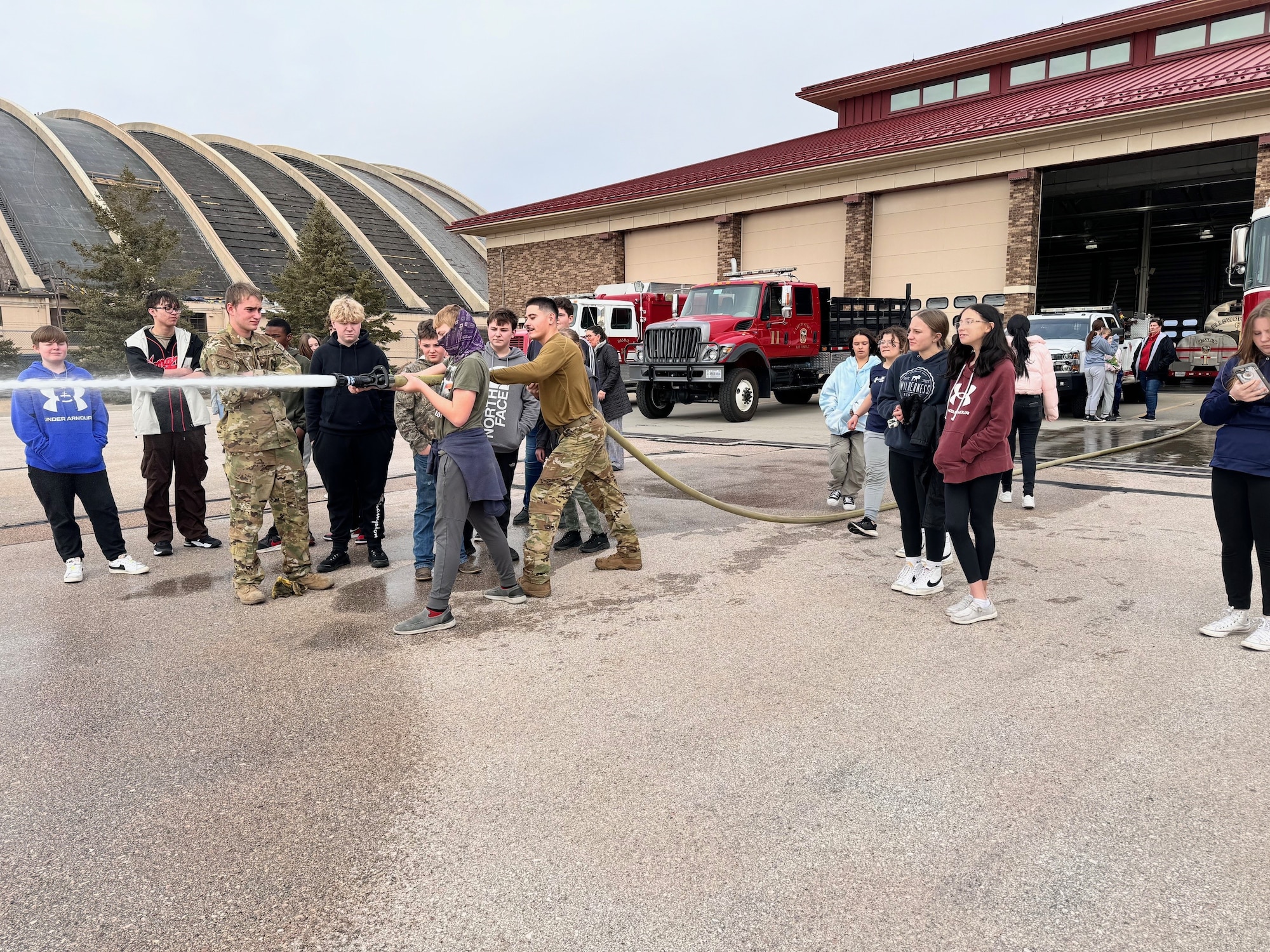 Students from Douglas Middle School use a fire hose at the 28th Civil Engineer Squadron fire department at Ellsworth Air Force Base, South Dakota, Dec. 5, 2023.