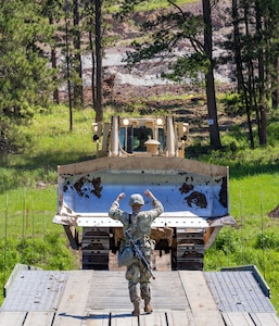 South Dakota Army National Guard horizontal engineers operate and guide a bulldozer over a bridge during the 2023 Golden Coyote training exercise as they worked on the future South Dakota School of Mines Geological Field House site near Nemo, S.D., June 6, 2023. This project is one of many being completed by the South Dakota National Guard in the Black Hills area during Golden Coyote 2023, the training provides both training for Soldiers and tangible benefits to the community.