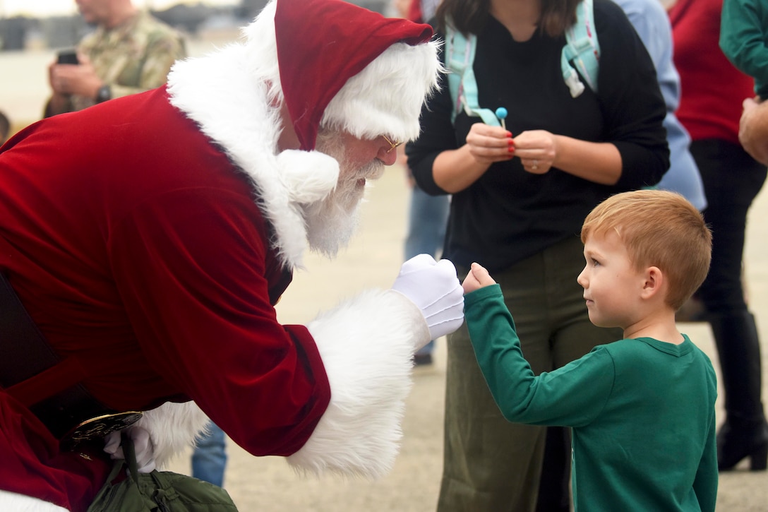 A close-up of a military child fist-bumping Santa.