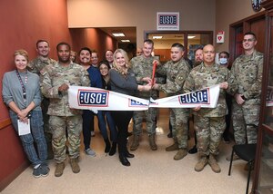 Crowd of people cutting a ribbon.