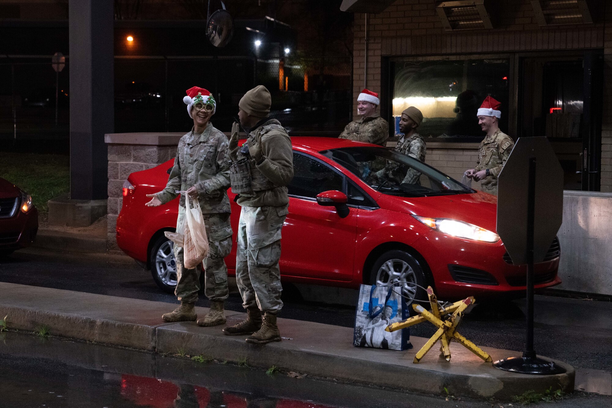 people in military uniforms hand out candy canes to people in cars