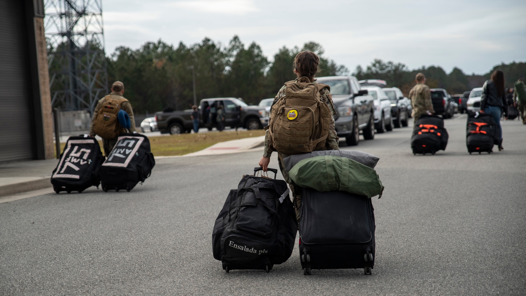 Airmen drag bags across a parking lot