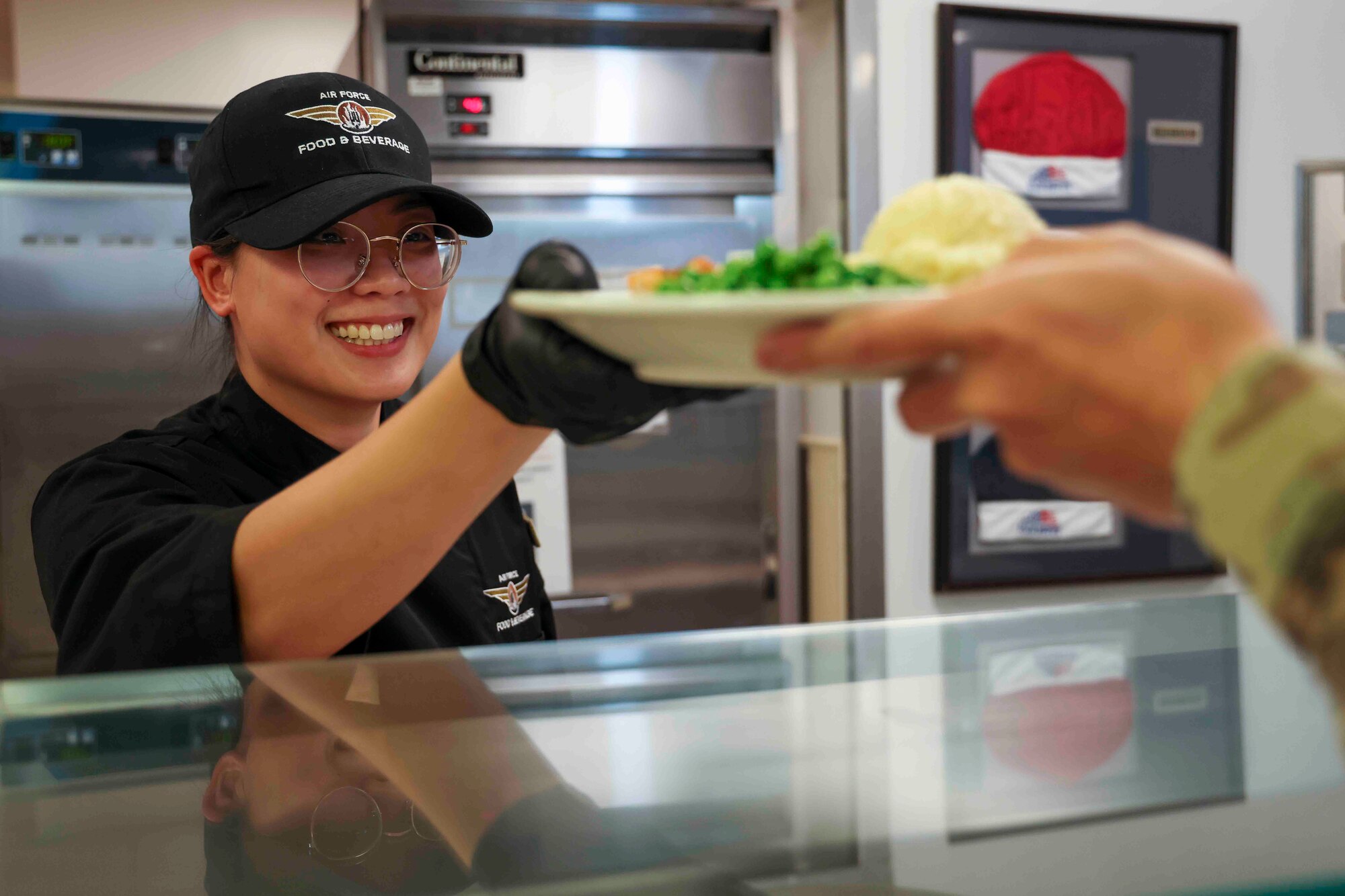 U.S. Air Force Airman 1st Class Trieu Do, 9th Force Support Squadron food service specialist, serves food to an Airman at the Contrails Dining Facility on Beale Air Force Base, California, Nov. 27, 2023.