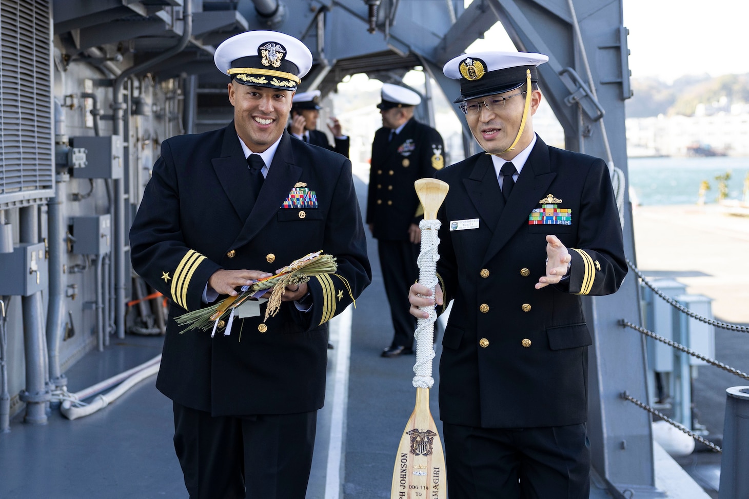 231207-N-NF288-0168 YOKOSUKA, Japan (Dec. 7, 2023) Cmdr. Justan Caesar, executive officer of the Arleigh Burke-class guided-missile destroyer USS Ralph Johnson (DDG 114), left, speaks with Lt. Cmdr. Tomita Naoaki, executive officer of the Asagiri-class destroyer JS Amagiri (DD-154), right, during the annual sister ship traditional gift exchange, Dec. 7. Ralph Johnson is forward-deployed and assigned to Commander, Task Force 71/Destroyer Squadron (DESRON) 15, the Navy’s largest DESRON and the U.S. 7th Fleet’s principal surface force. (U.S. Navy photo by Mass Communication Specialist 1st Class Jamaal Liddell)
