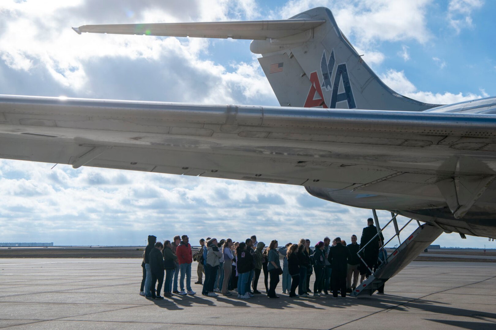 a group of high school students gather near an aircraft tail