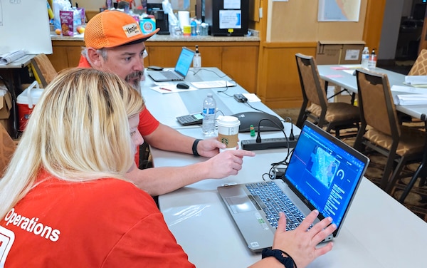 Emergency Field Office GIS analyst Bill Sisneros explains to environmental scientist Jean Barnes how to use a GIS-created application for the 2023 Hawai'i Wildfire data collection.