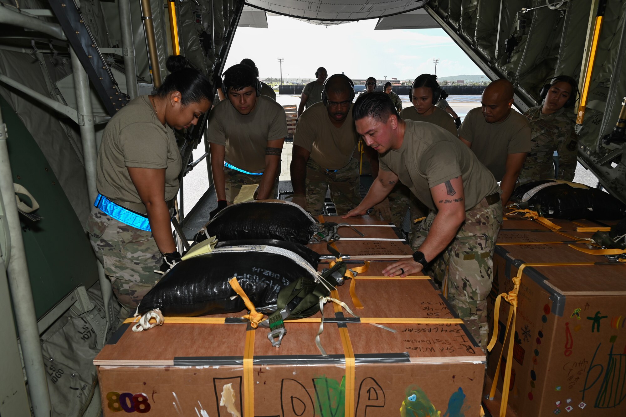 Several Airmen some from Joint Base Charleston, South Carolina, Andersen Air Force Base, Guam and Yokota Air Base, Japan work together to load a C-130J Super Hercules with bundles of humanitarian aid.