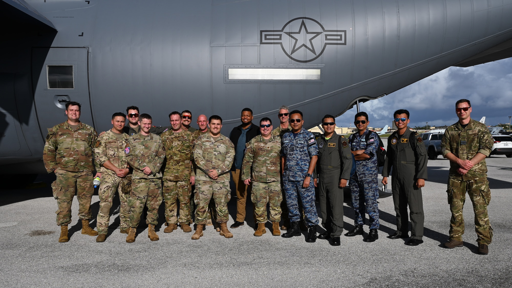 U.S. Air Force Airmen pose for a group photo with foreign allies in front of a C-130J Super Hercules.