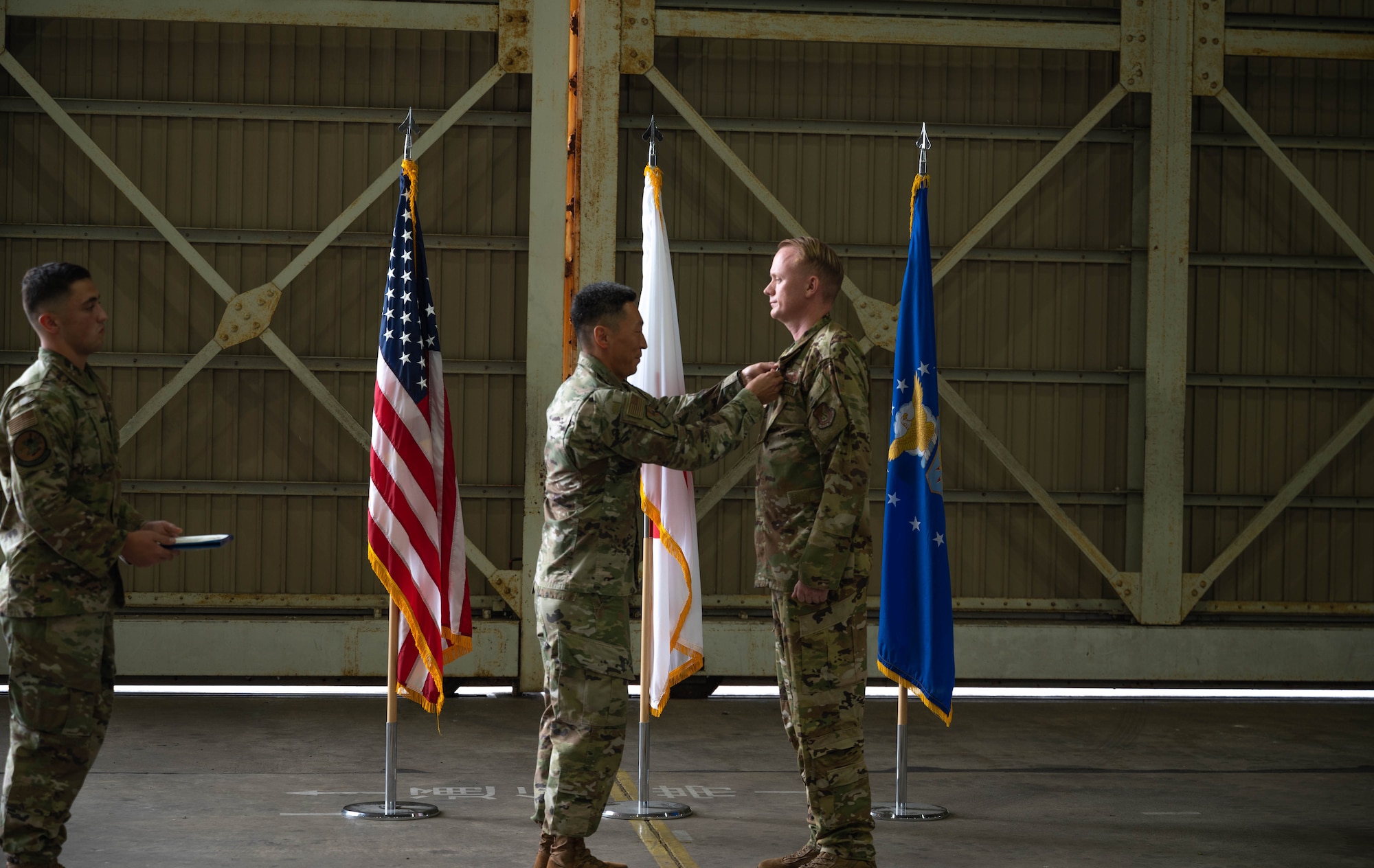 U.S. Air Force Colonel Jun Oh of the 374th Operation Group, awards Lieutenant Colonel Alexander Kelly, commanding officer of the 319th Expeditionary Reconnaissance Squadron, the Meritorious Service Medal at Japan Maritime Self-Defense Force Kanoya Air Base, Oct. 13, 2023.