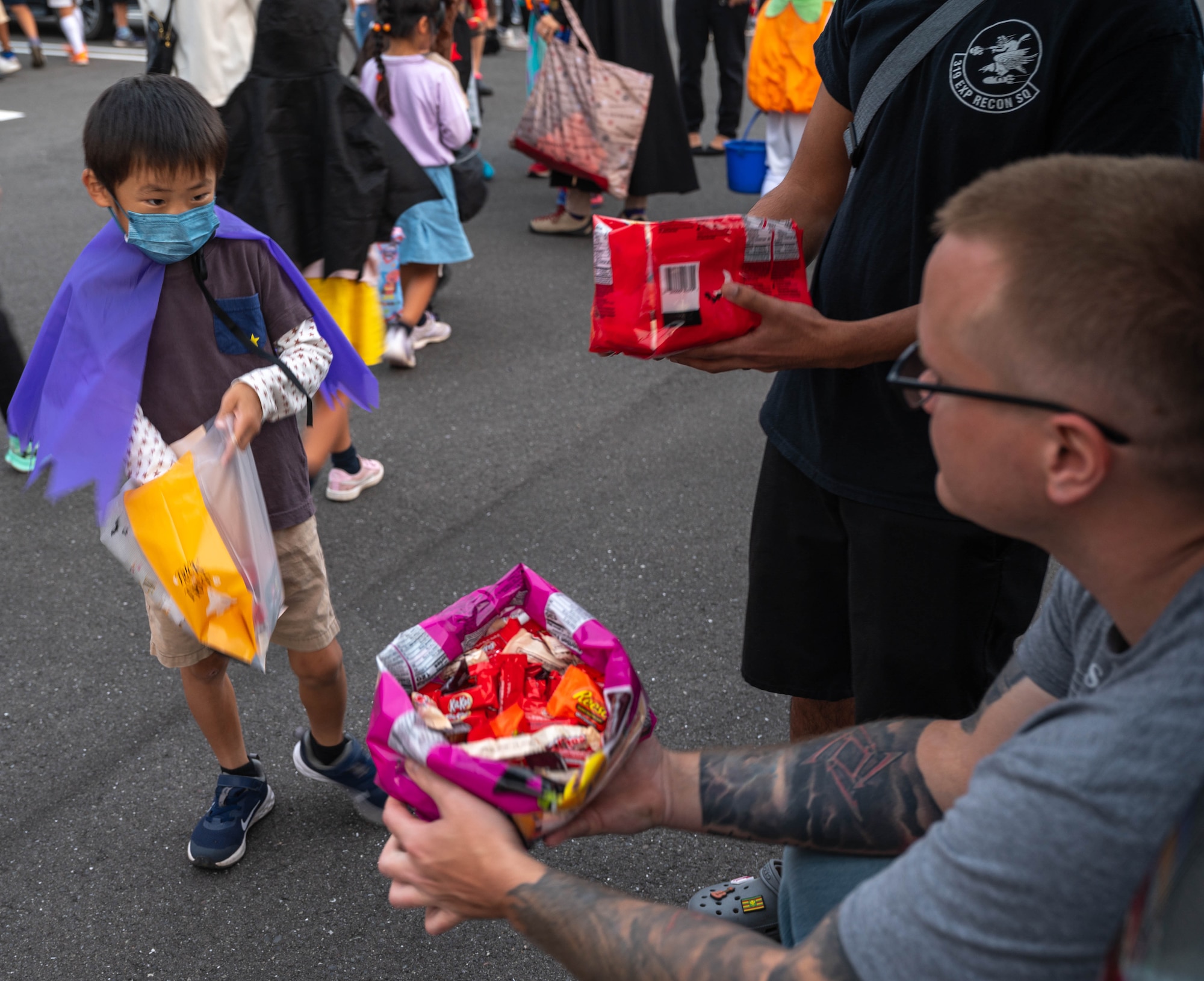 TSgt Mathew Scheuer, non-commissioned officer in charge of fuel operations, 319th Expeditionary Reconnaissance Squadron, hands out candy during the Trunk-or-Treat event at Kanoya, Japan, Oct. 13th 2023.