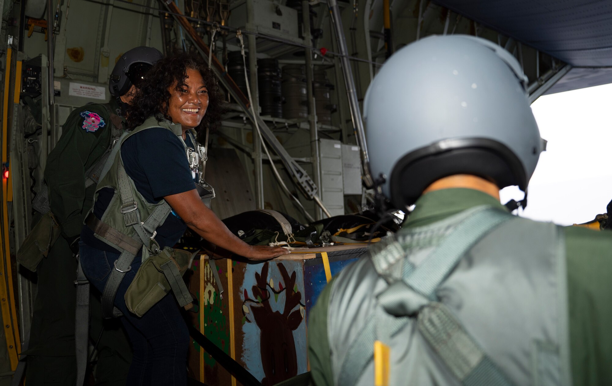 Nanako Lipai, a Mokil Atoll native, watches a member of the Japan Air Self-Defense Force 401st Tactical Airlift Squadron as they prepare to airdrop bundles of humanitarian aid during Operation Christmas Drop 2023 (OCD 23) above the Federated States of Micronesia, Dec. 6, 2023. This was Lipai’s third time flying during OCD but it was the first time she got to fly to her home island to drop supply bundles. Through the international cooperation and the enduring commitment of the U.S. Air Force and its allies and partners, OCD has become a testament to the power of collaboration and shared humanity. (U.S. Air Force photo by Airman 1st Class Spencer Perkins)