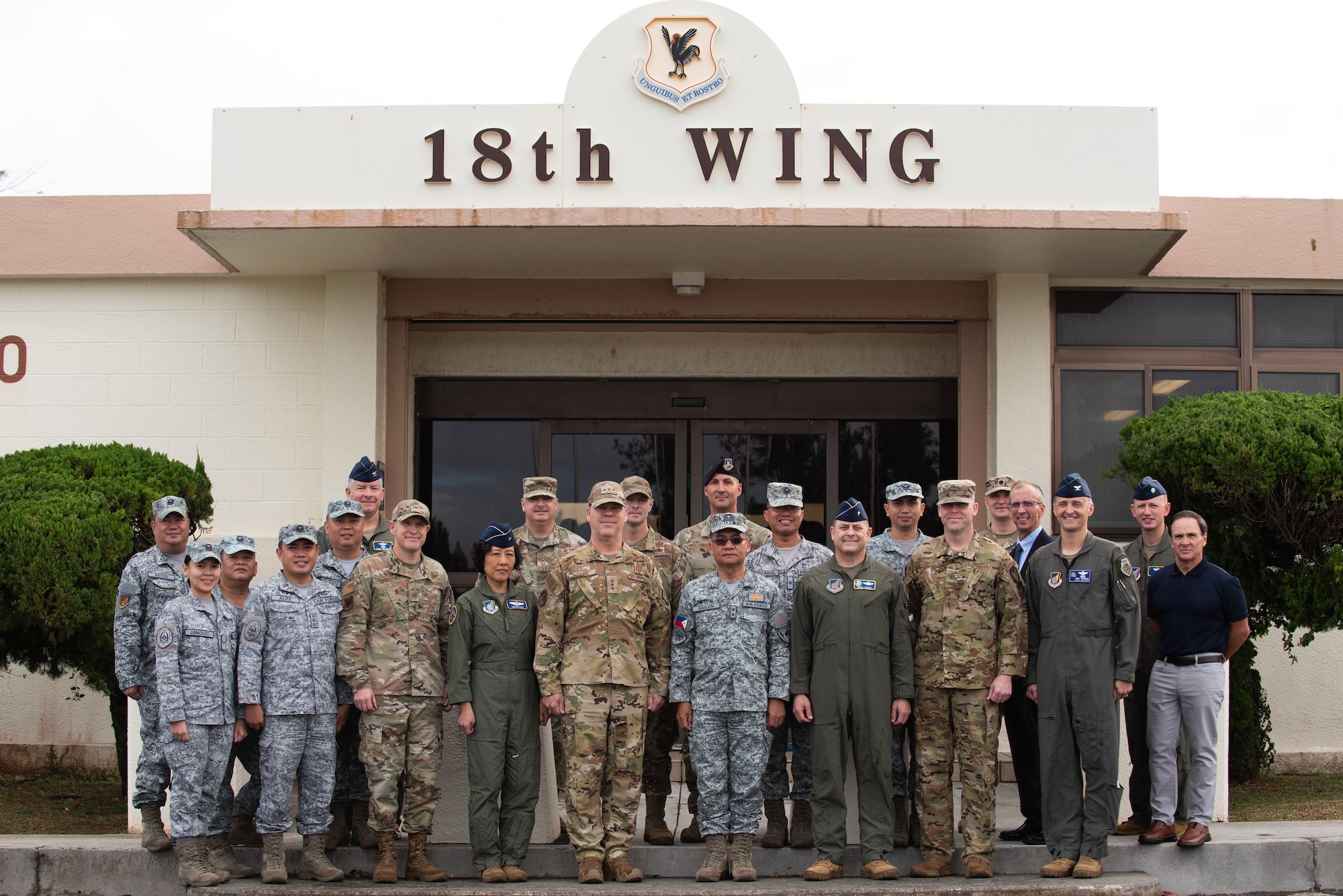 military members pose for a portrait in front of higher headquarters building