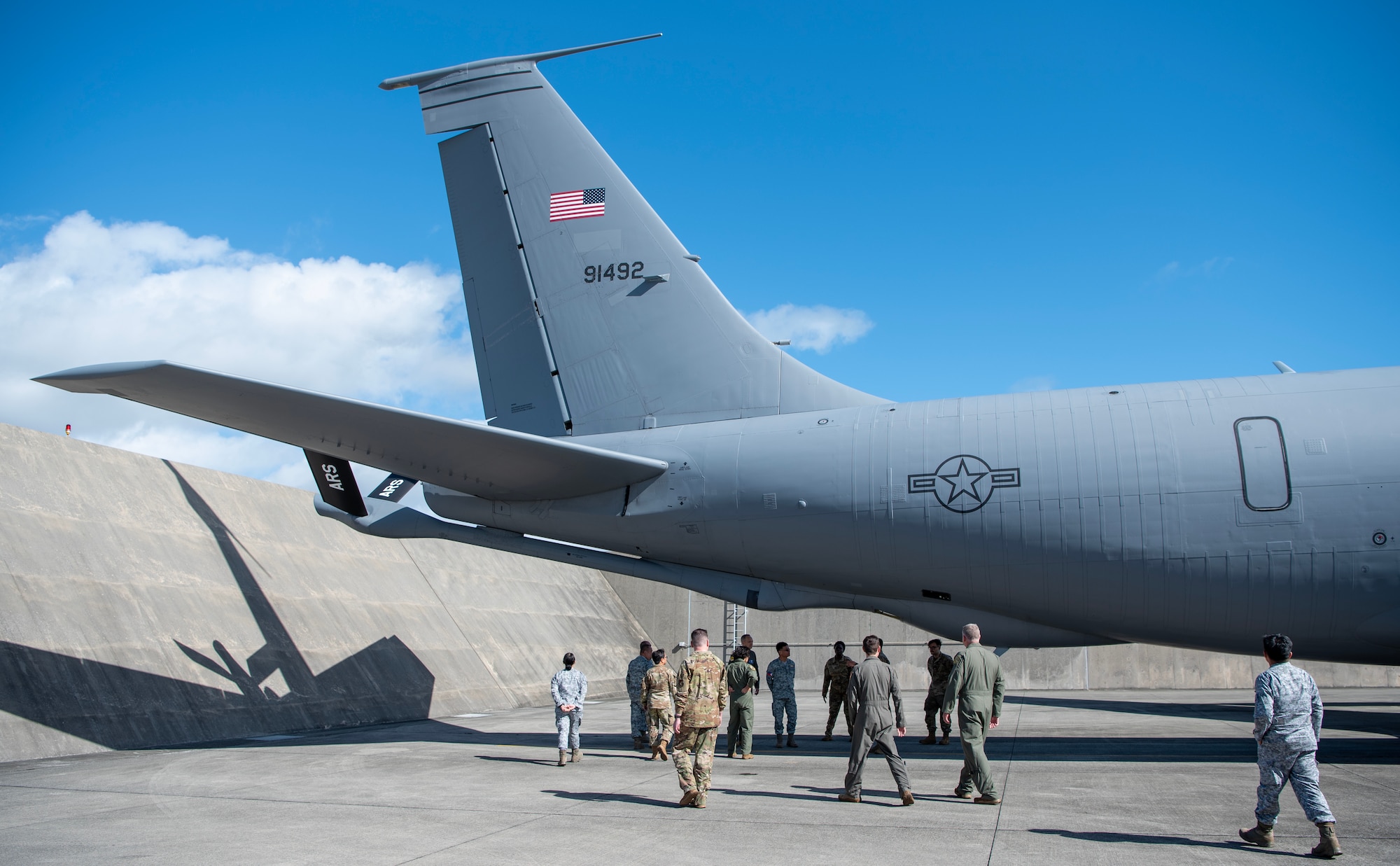 military members walk around a plane looking at its underbelly