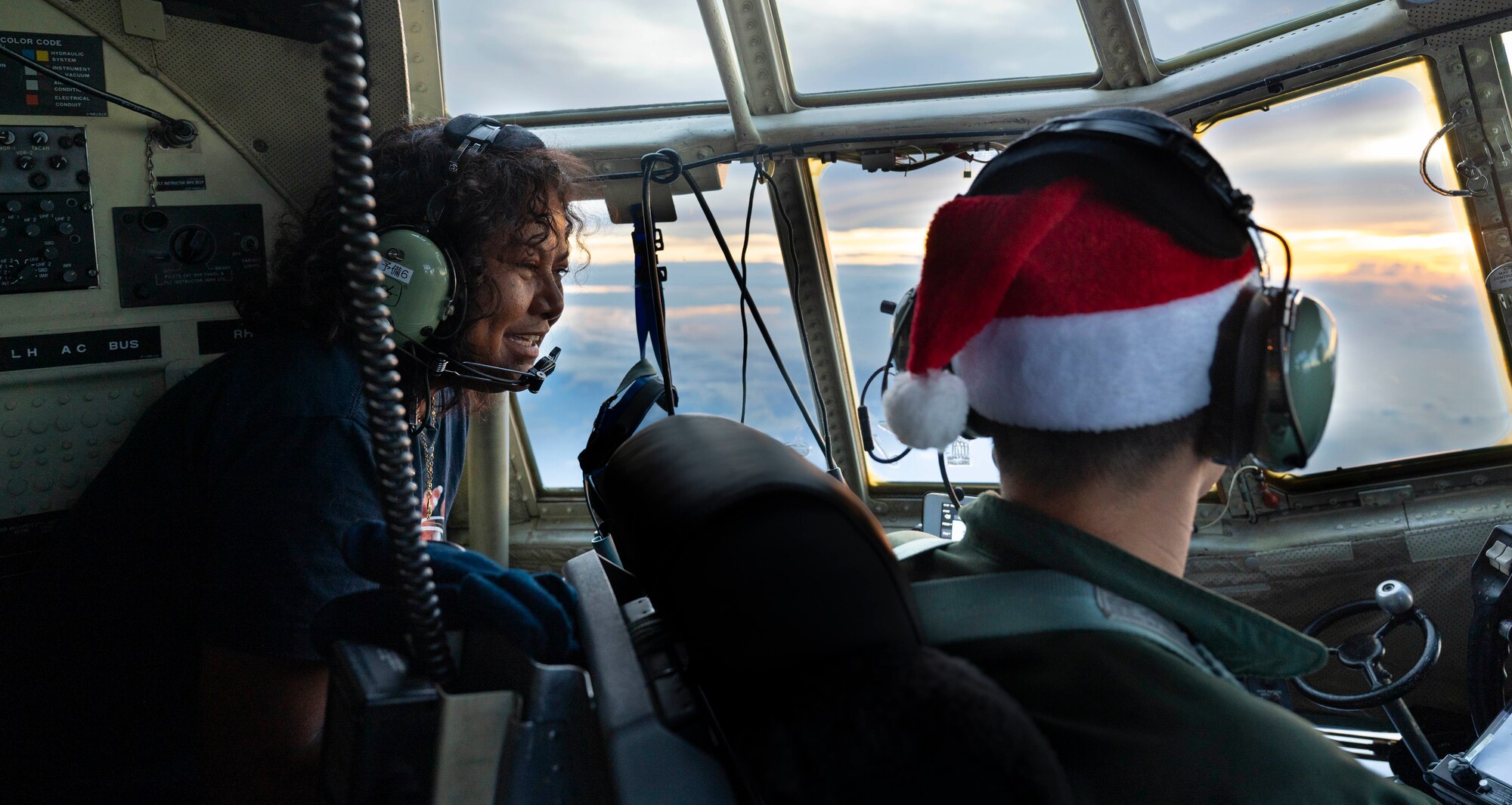 Nanako Lipai, a Mokil Atoll native, talks with Japan Air Self-Defense Force Maj. Kentaro Hirai, 401st Tactical Airlift Squadron pilot, during a flight in support of Operation Christmas Drop 2023 (OCD 23) above the Federated States of Micronesia, Dec. 6, 2023. This was Lipai’s third time flying during OCD but it was the first time she got to fly to her home island to drop supply bundles. (U.S. Air Force photo by Airman 1st Class Spencer Perkins)