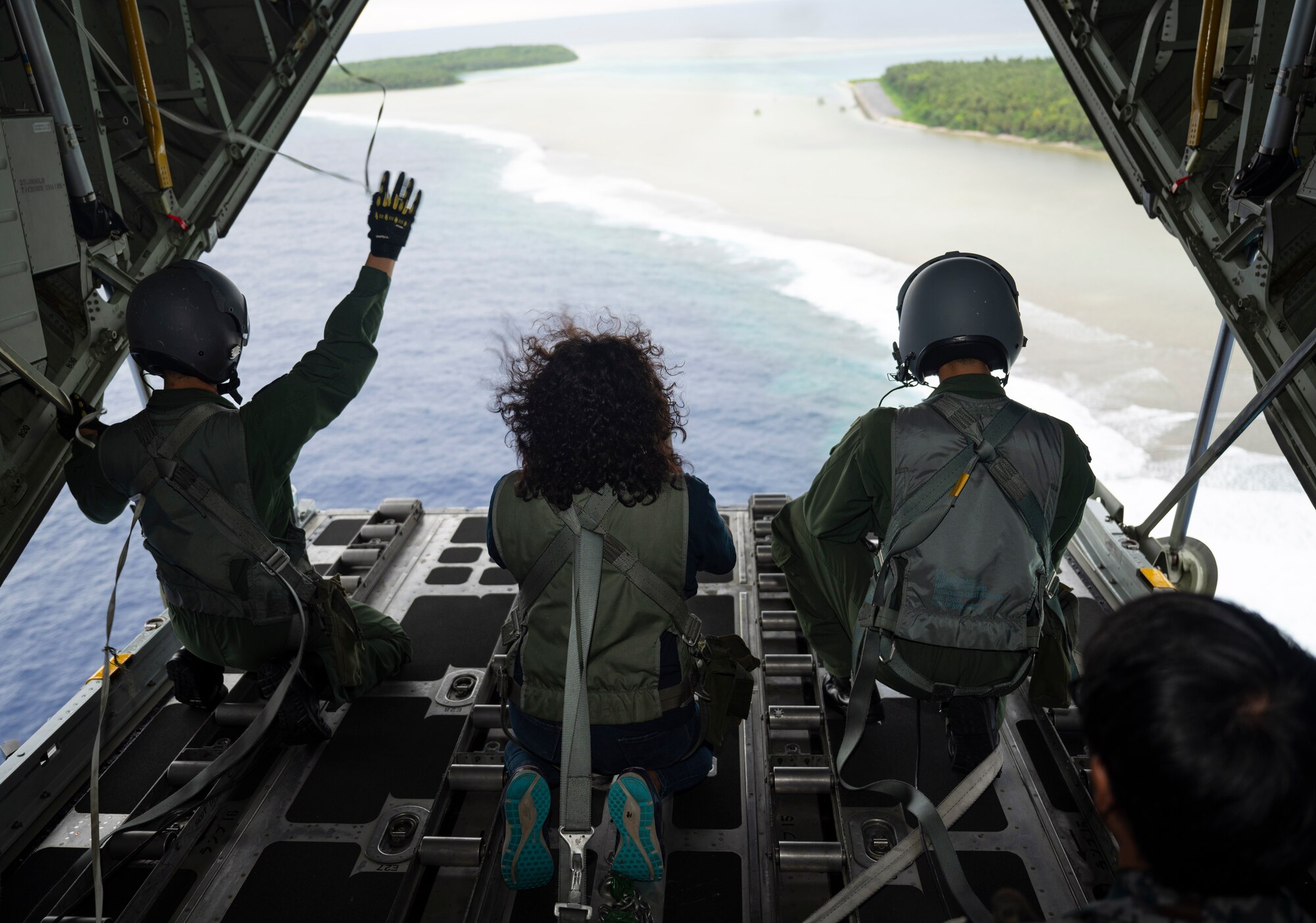 Nanako Lipai, a Mokil Atoll native, and members of the Japan Air Self-Defense Force 401st Tactical Airlift Squadron look out of a Japan Air Self-Defense Force C-130H Hercules after dropping bundles of humanitarian aid over Mokil Atoll during Operation Christmas Drop 2023 (OCD 23) Dec. 6, 2023. This was Lipai’s third time flying during OCD but it was the first time she got to fly to her home island to drop supply bundles. Through the international cooperation and the enduring commitment of the U.S. Air Force and its allies and partners, OCD has become a testament to the power of collaboration and shared humanity. (U.S. Air Force photo by Airman 1st Class Spencer Perkins)