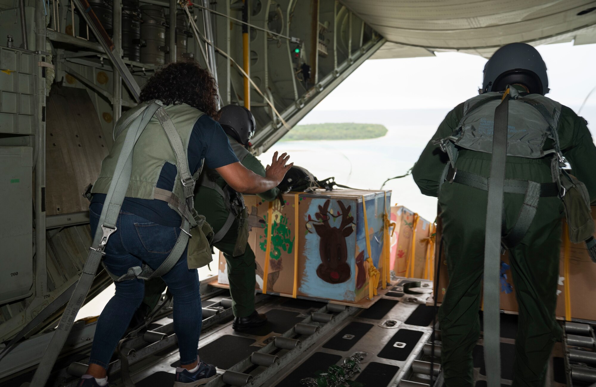 Nanako Lipai, a Mokil Atoll native, and members of the Japan Air Self-Defense Force (JASDF) 401st Tactical Airlift Squadron push bundles of humanitarian aid out of a JASDF C-130H Hercules during Operation Christmas Drop 2023 (OCD 23) over Mokil Atoll, Dec. 6, 2023. This was Lipai’s third time flying during OCD but it was the first time she got to fly to her home island to drop supply bundles. Through the international cooperation and the enduring commitment of the U.S. Air Force and its allies and partners, OCD has become a testament to the power of collaboration and shared humanity. (U.S. Air Force photo by Airman 1st Class Spencer Perkins)